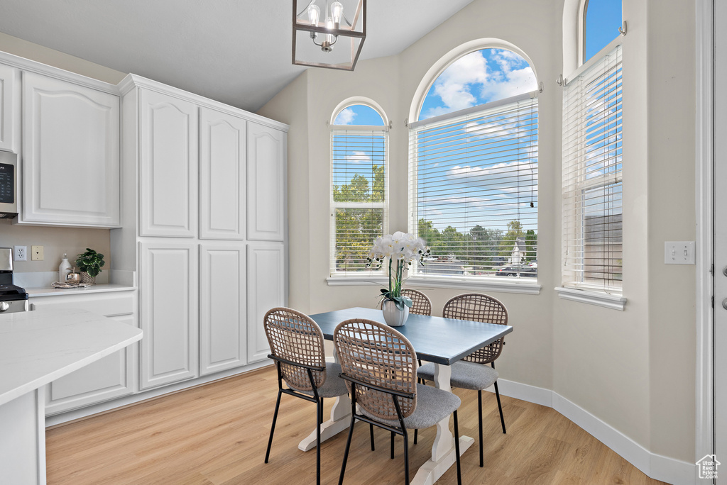 Dining area with light wood-type flooring, a chandelier, and plenty of natural light