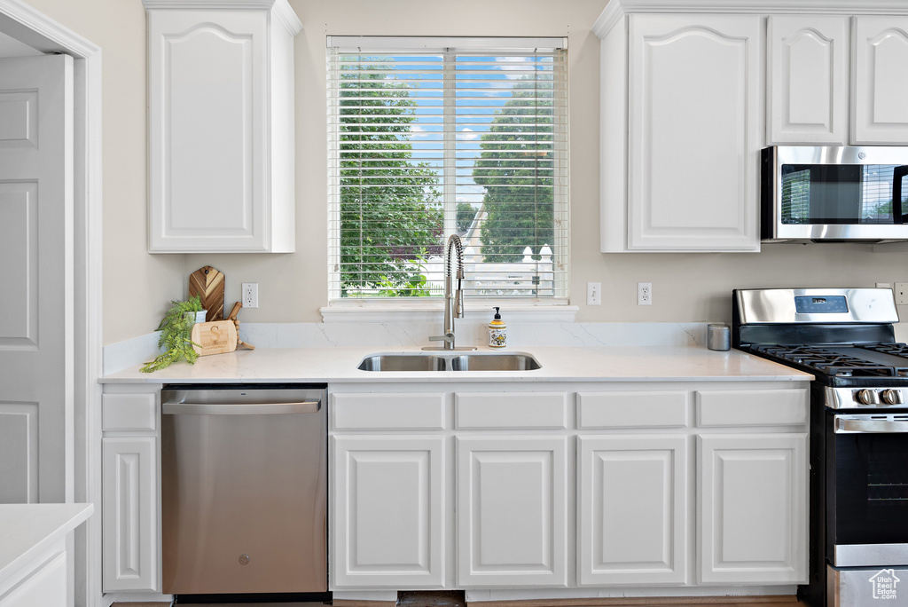 Kitchen with stainless steel appliances, white cabinetry, healthy amount of natural light, and light countertops