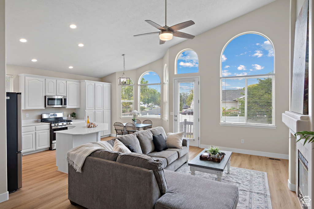 Living area featuring plenty of natural light, light wood-type flooring, ceiling fan, vaulted ceiling, and recessed lighting