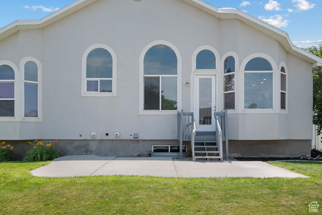 View of front facade featuring a front lawn, a patio, and stucco siding