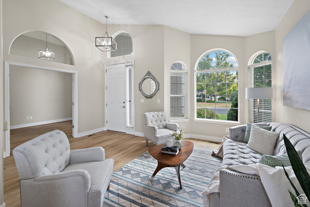 Living area with a chandelier, wood finished floors, and high vaulted ceiling