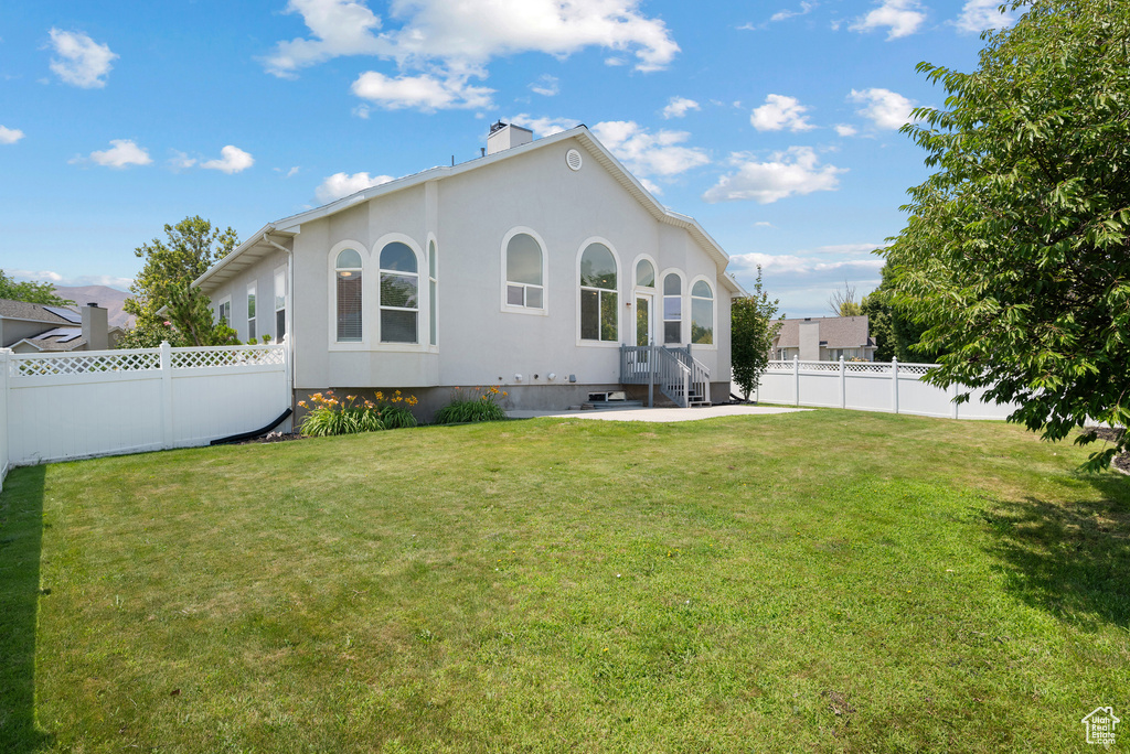 Back of house with stucco siding, a fenced backyard, and a chimney