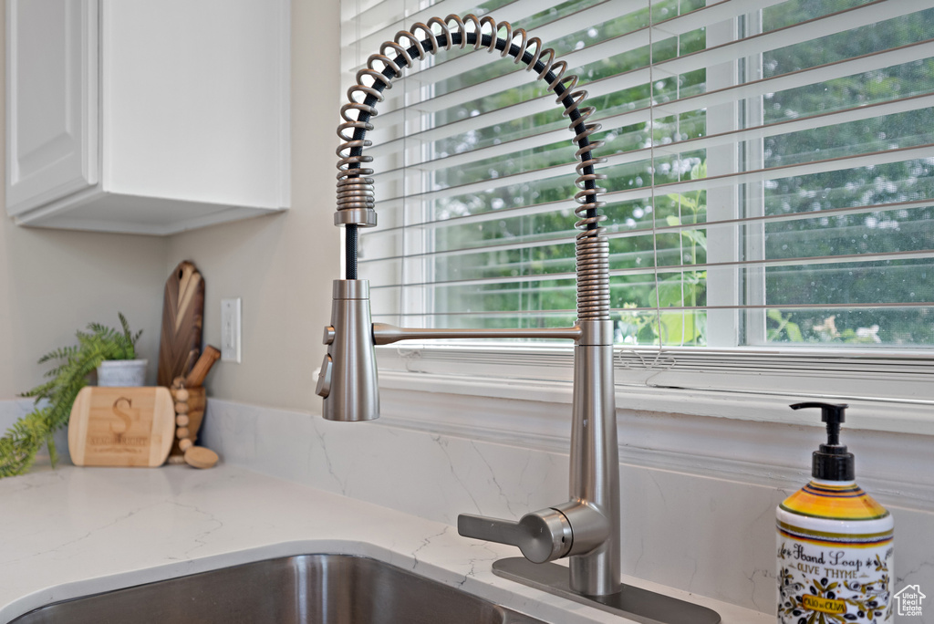 Kitchen view of white cabinetry and light stone counters
