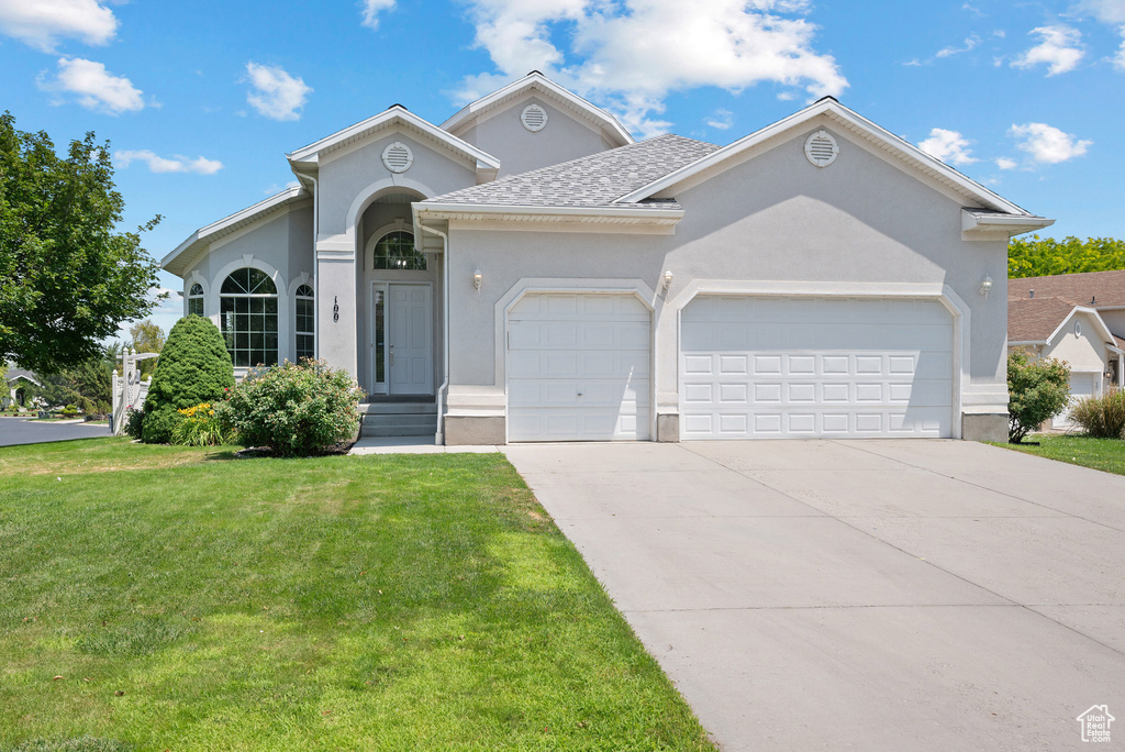 Single story home with stucco siding, a front lawn, a garage, driveway, and roof with shingles