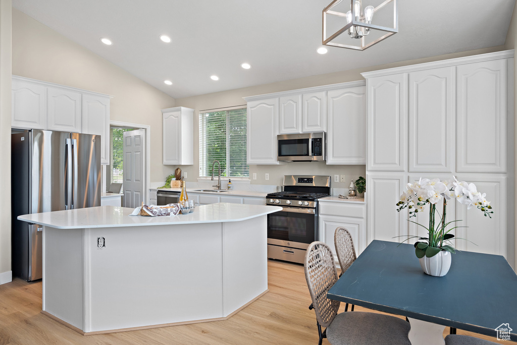 Kitchen featuring appliances with stainless steel finishes, a center island, white cabinetry, light wood finished floors, and recessed lighting
