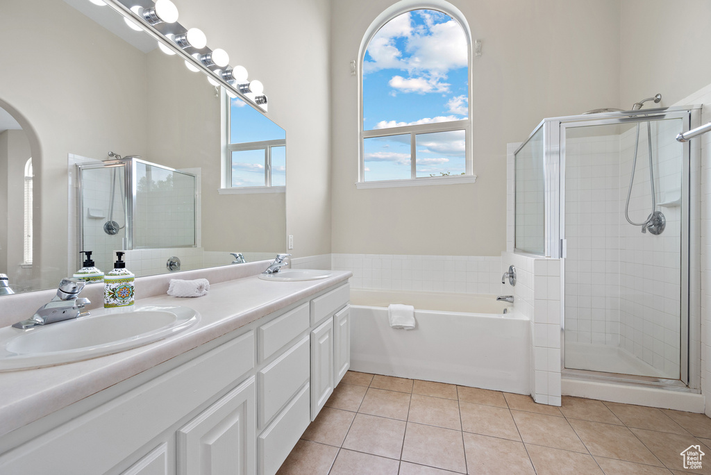 Bathroom featuring double vanity, a stall shower, a garden tub, and tile patterned floors
