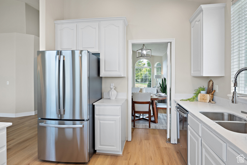 Kitchen featuring appliances with stainless steel finishes, light wood-type flooring, white cabinets, and light countertops
