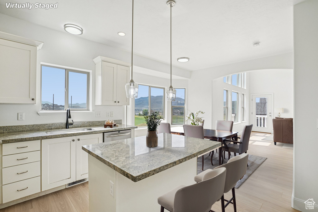 Kitchen with a kitchen island, light wood finished floors, white cabinetry, a breakfast bar area, and recessed lighting
