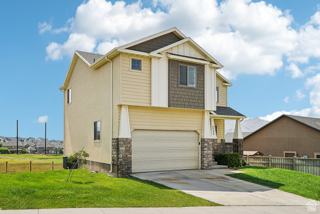 Craftsman-style house with driveway, a garage, stone siding, and board and batten siding