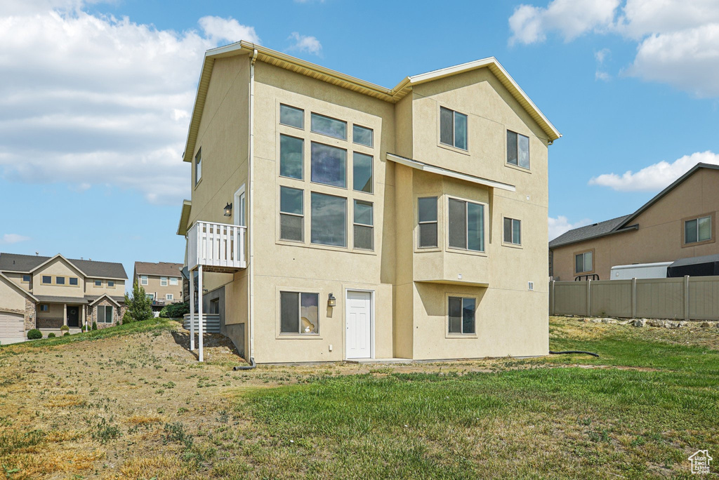 Back of house with stucco siding and a lawn