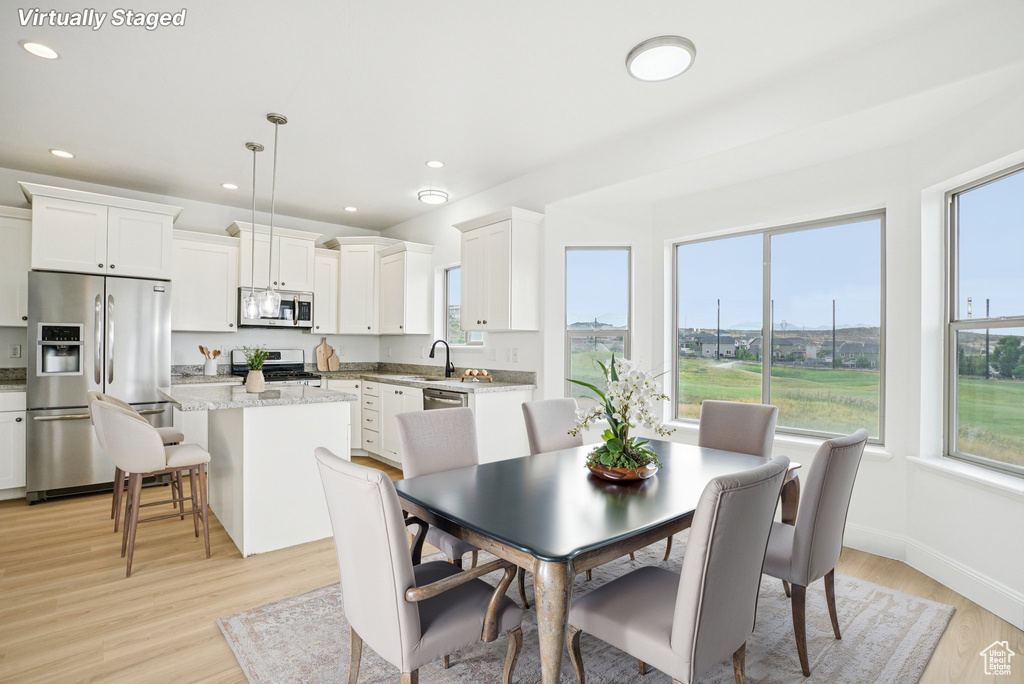Dining area with light wood finished floors and recessed lighting