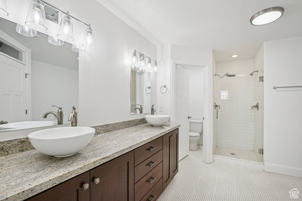 Bathroom featuring a stall shower, double vanity, tile patterned flooring, and recessed lighting