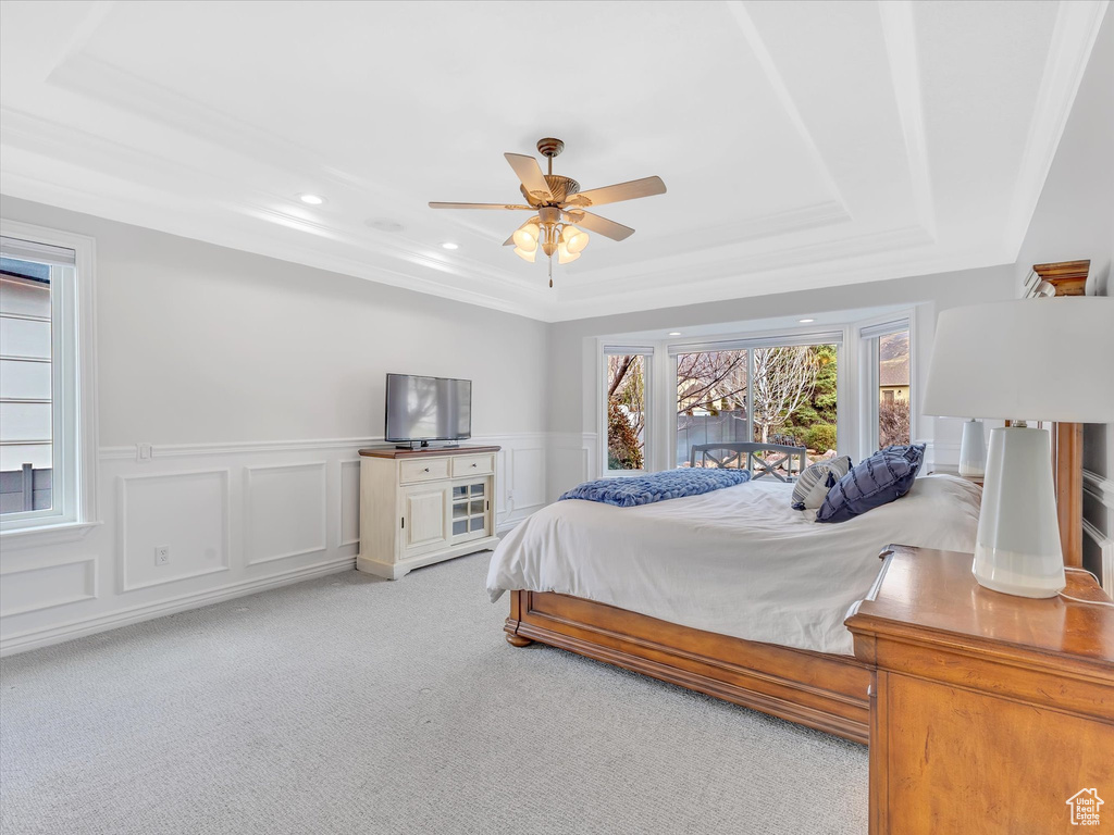 Carpeted bedroom featuring a tray ceiling, wainscoting, recessed lighting, a ceiling fan, and a decorative wall