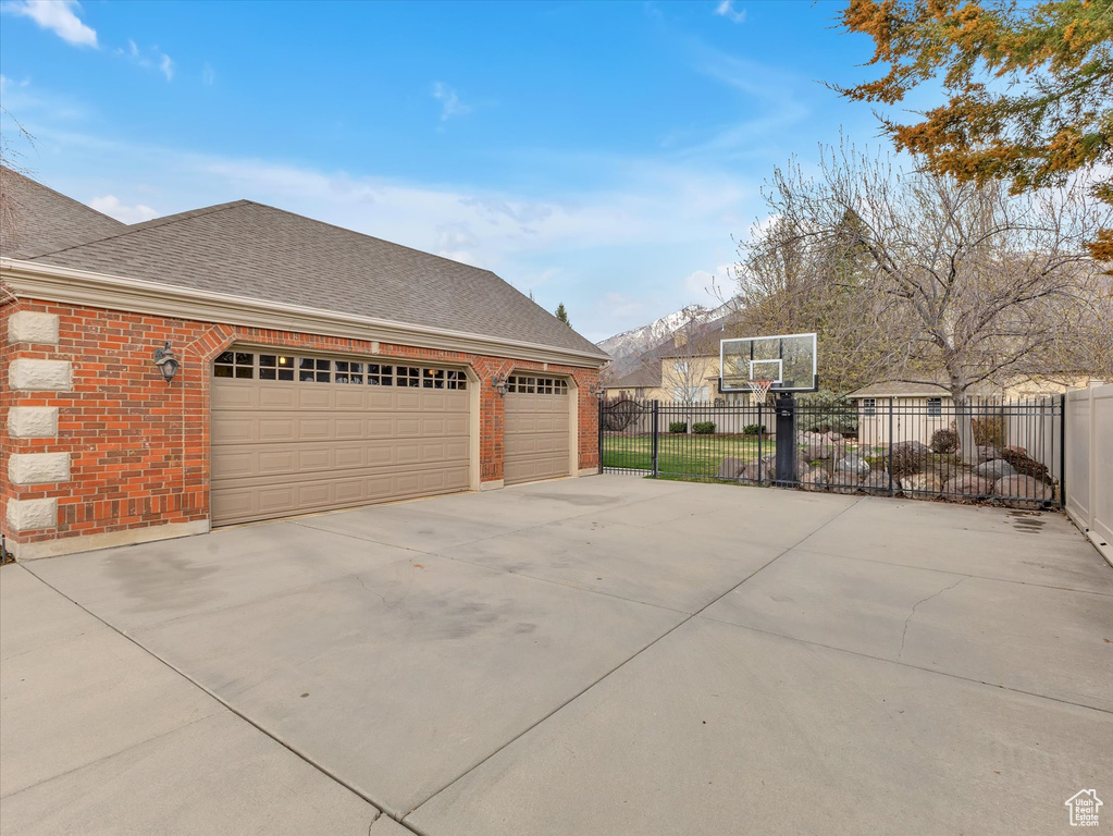 View of side of home with roof with shingles, brick siding, and concrete driveway