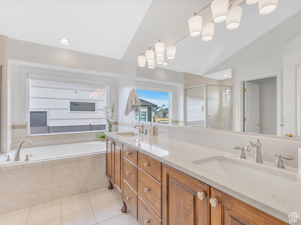 Bathroom featuring vaulted ceiling, tile patterned floors, a shower stall, double vanity, and a garden tub