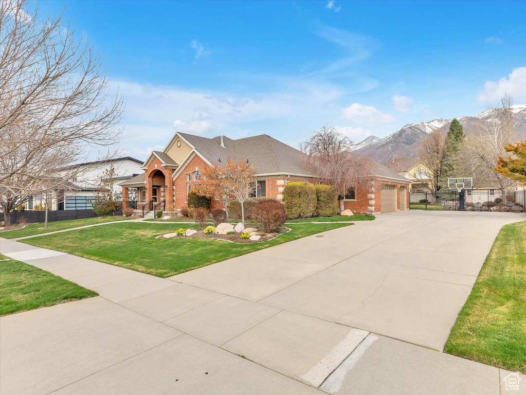 View of front of home featuring brick siding, a garage, driveway, and a mountain view