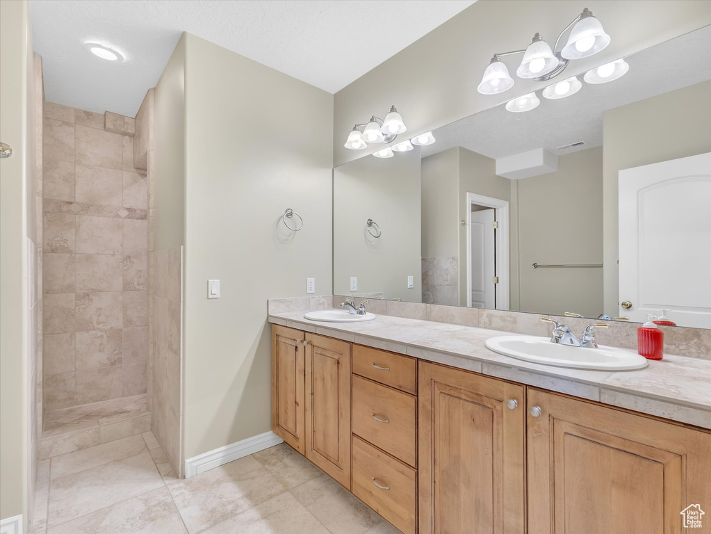 Full bath with double vanity, a walk in shower, and tile patterned flooring