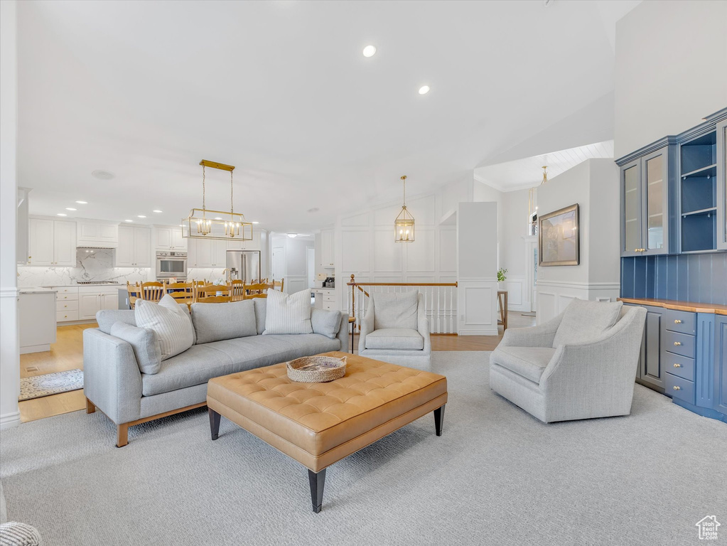 Living area with a decorative wall, recessed lighting, vaulted ceiling, a wainscoted wall, and light colored carpet