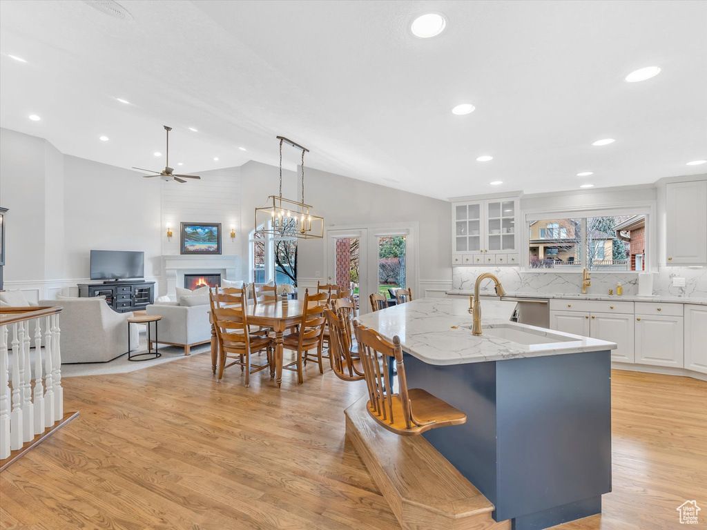 Kitchen featuring a fireplace, a ceiling fan, vaulted ceiling, a decorative wall, and light stone countertops