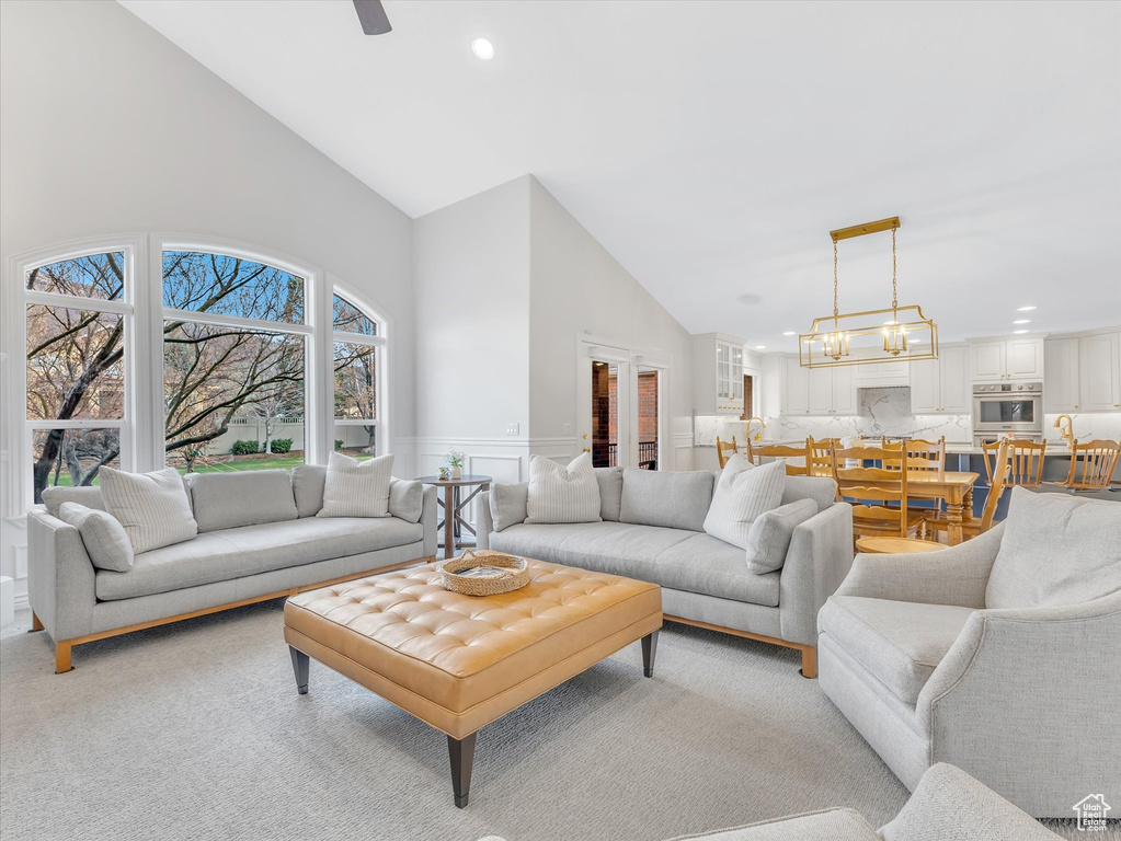 Living room featuring high vaulted ceiling, recessed lighting, a wainscoted wall, light colored carpet, and a decorative wall