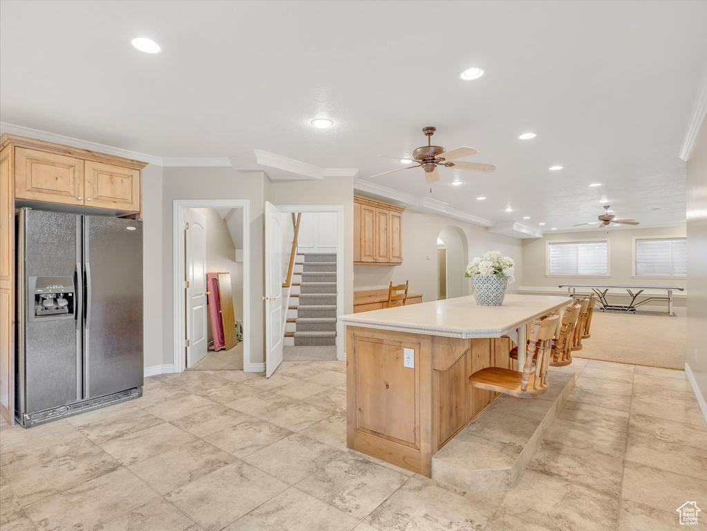 Kitchen with ceiling fan, light brown cabinets, black fridge, crown molding, and light countertops