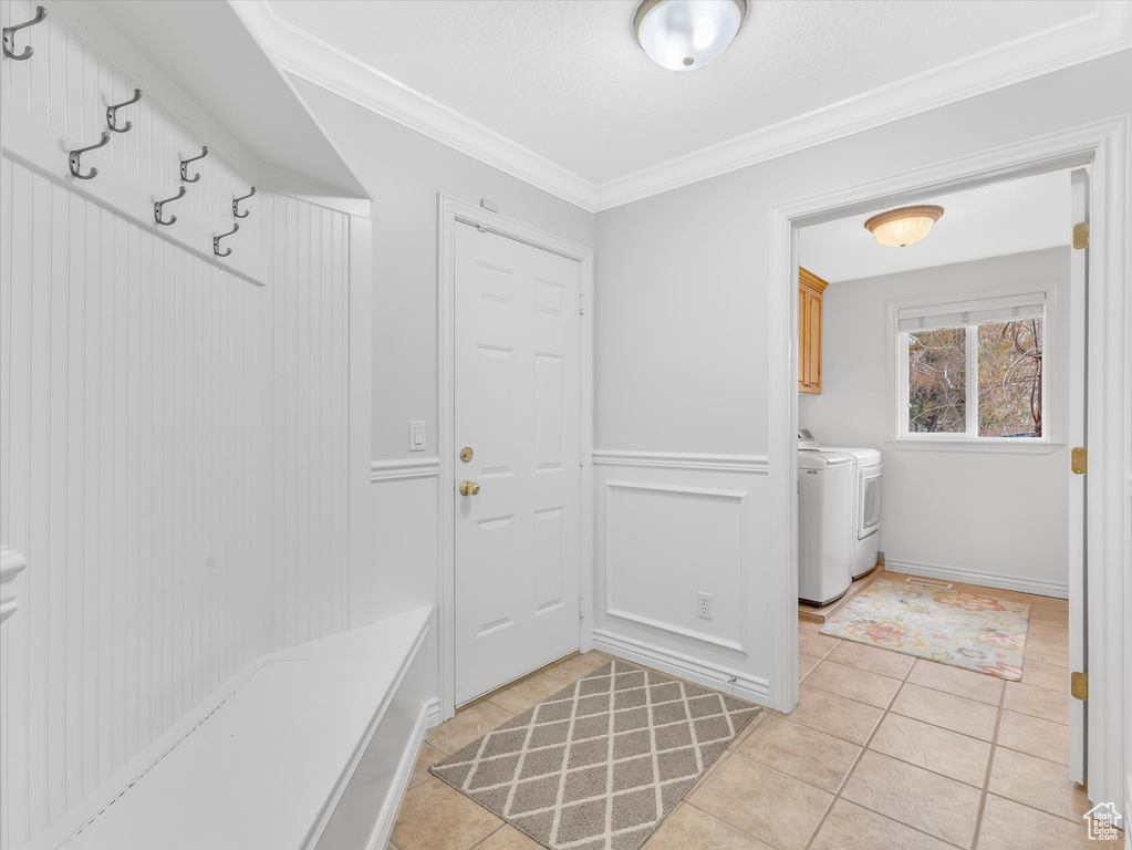 Mudroom with independent washer and dryer, crown molding, and light tile patterned flooring