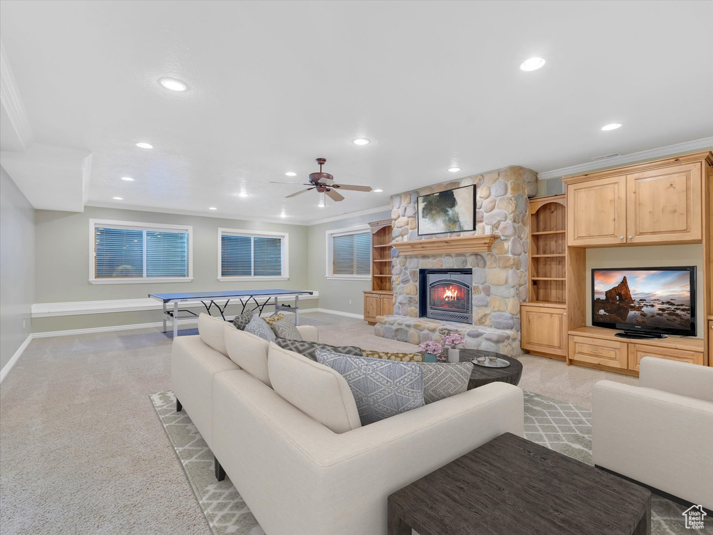 Living area featuring light carpet, ceiling fan, recessed lighting, ornamental molding, and a stone fireplace