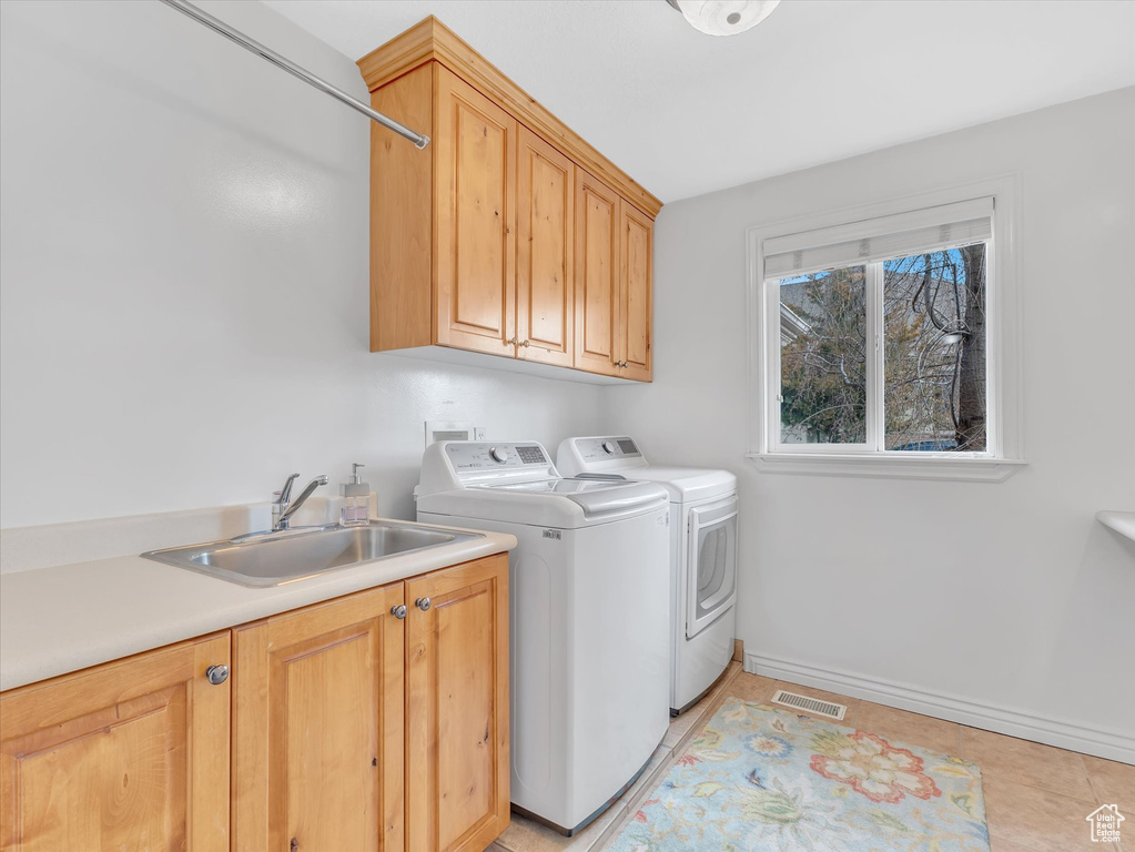 Laundry area featuring cabinet space, washing machine and dryer, and light tile patterned flooring