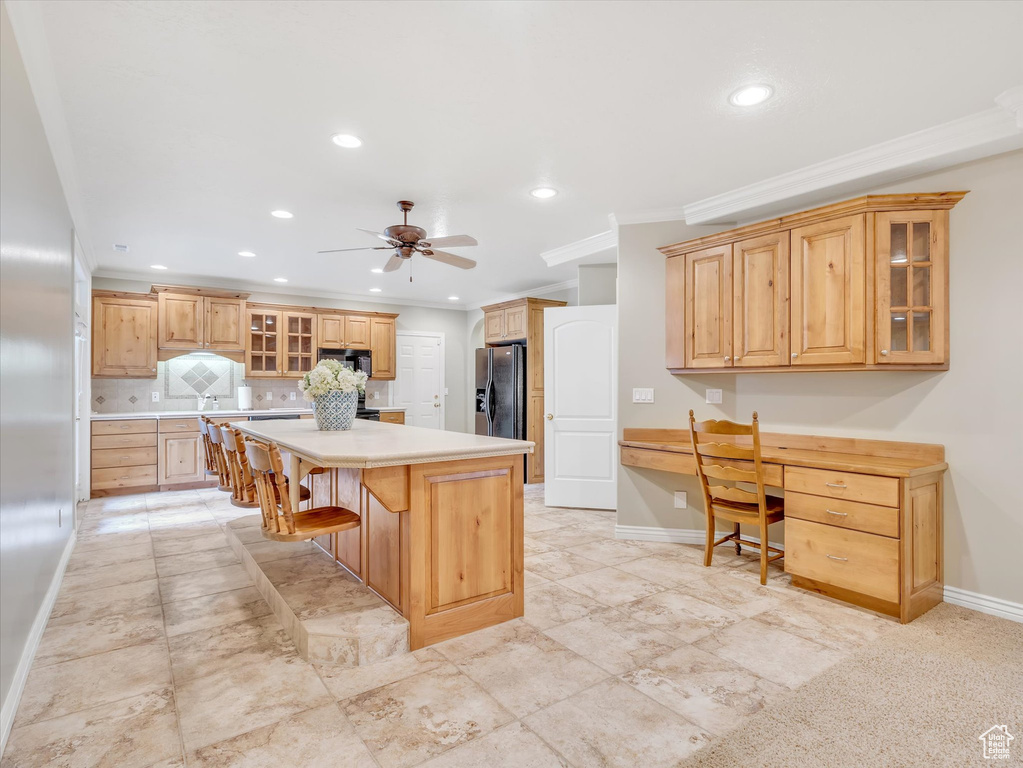 Kitchen with crown molding, a kitchen bar, tasteful backsplash, recessed lighting, and a kitchen island