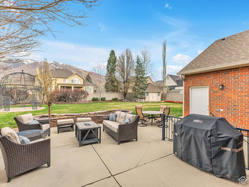 View of patio with an outdoor hangout area, area for grilling, a storage shed, a residential view, and a mountain view
