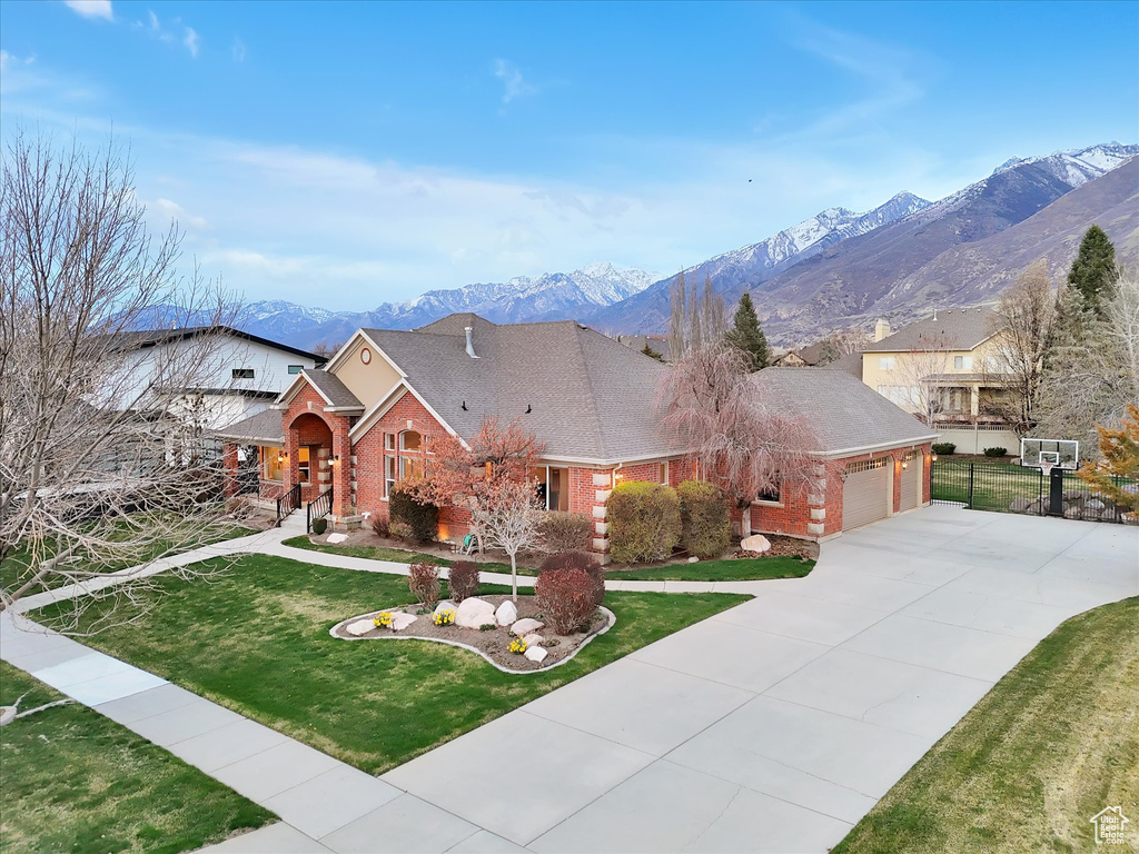 View of front of property with brick siding, a garage, concrete driveway, a mountain view, and a shingled roof