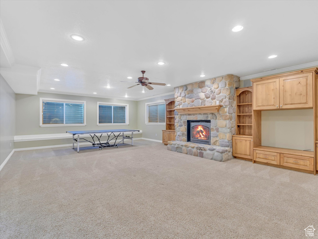 Living room with ornamental molding, carpet floors, a ceiling fan, recessed lighting, and a stone fireplace