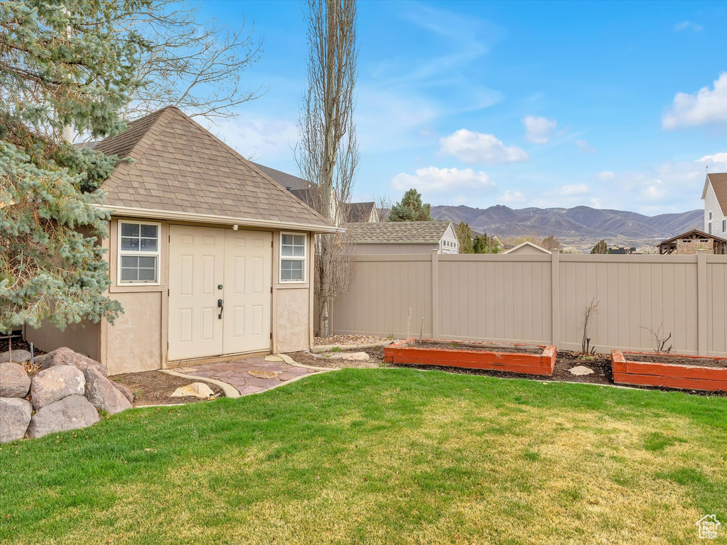 View of yard with a storage shed, a mountain view, and a vegetable garden