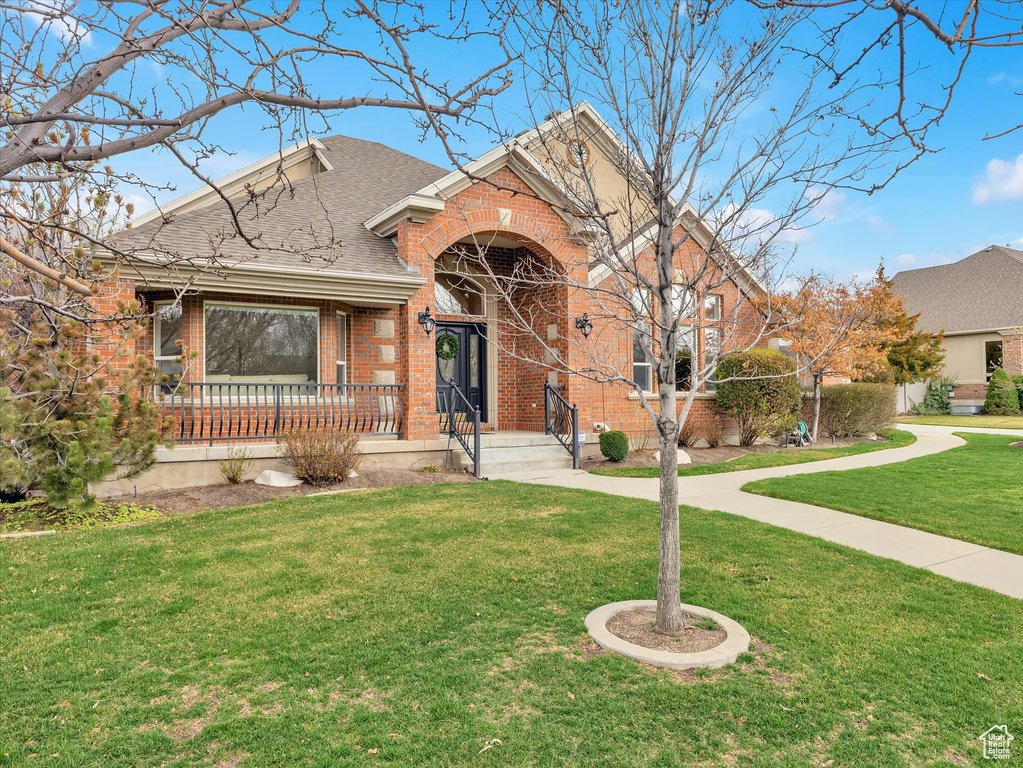 Tri-level home with brick siding, a front yard, and a shingled roof
