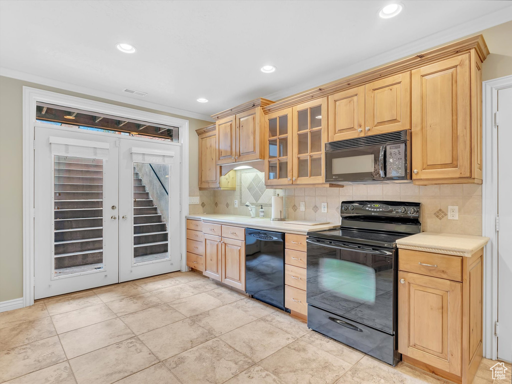 Kitchen with black appliances, light countertops, tasteful backsplash, light brown cabinets, and glass insert cabinets