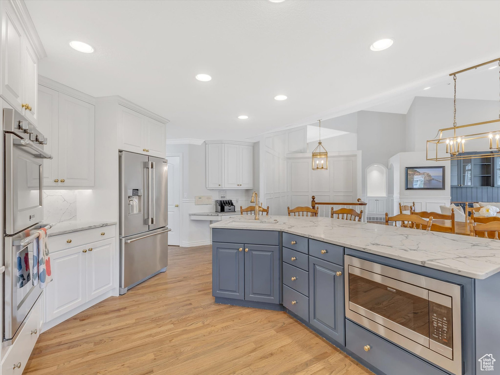 Kitchen with a chandelier, white cabinetry, stainless steel appliances, light wood-style flooring, and recessed lighting