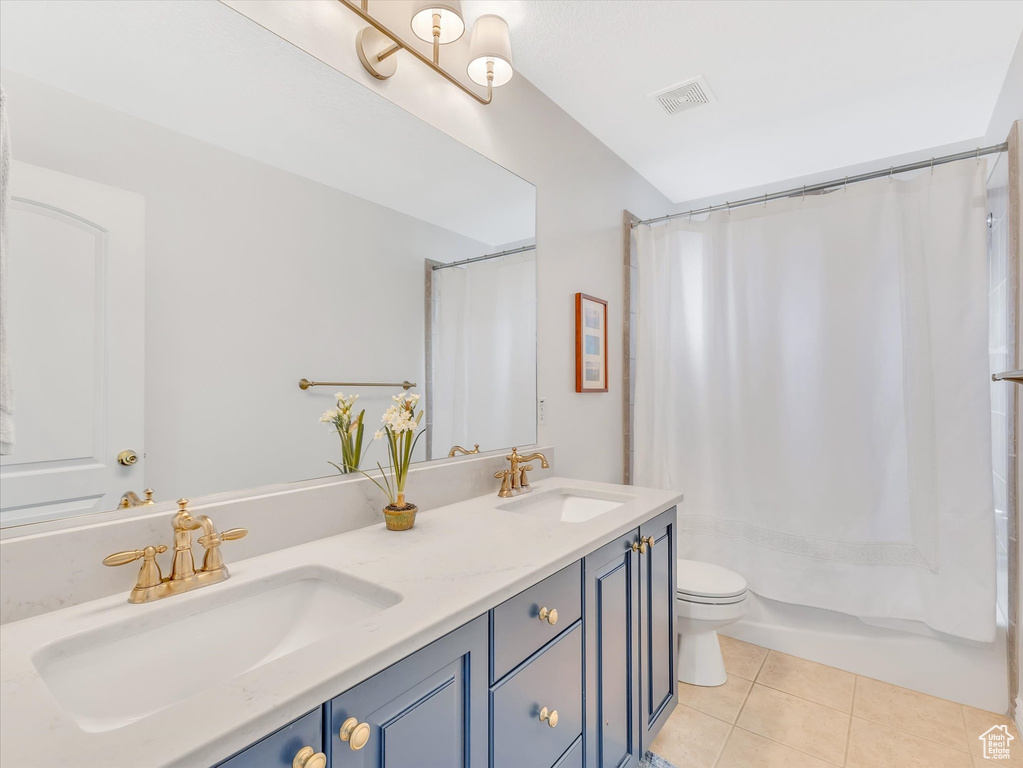 Bathroom featuring tile patterned floors, double vanity, and shower / tub combo