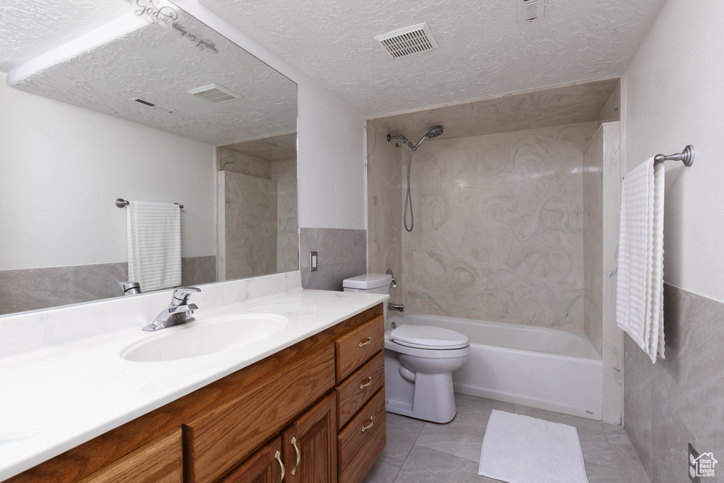 Full bathroom with vanity, shower / tub combination, a textured ceiling, and tile patterned flooring