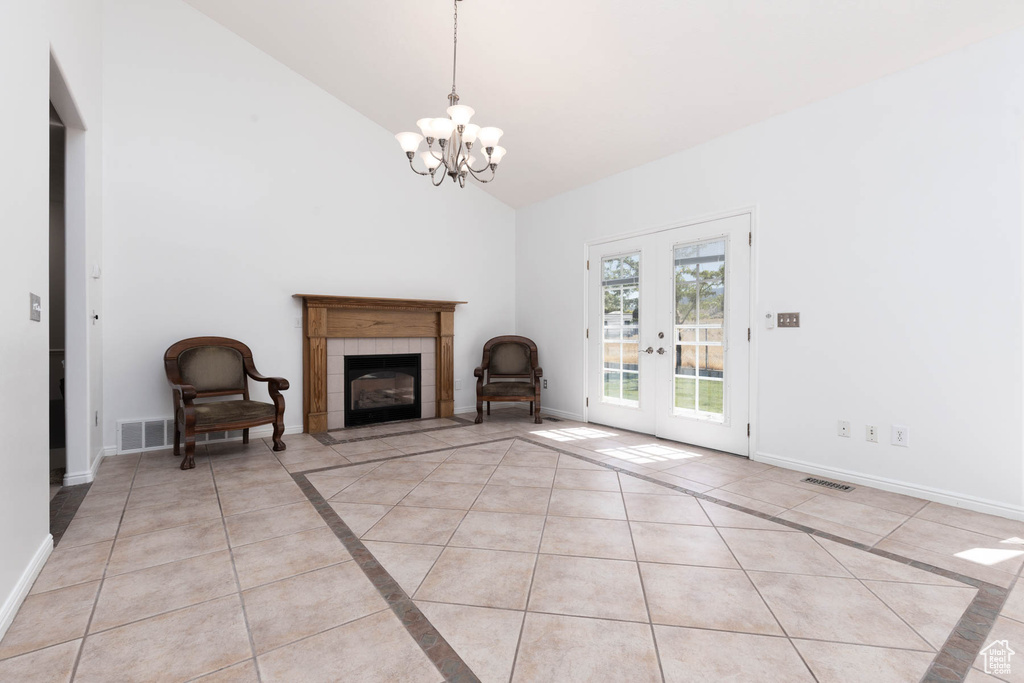 Unfurnished living room featuring light tile patterned floors, high vaulted ceiling, a chandelier, french doors, and a fireplace