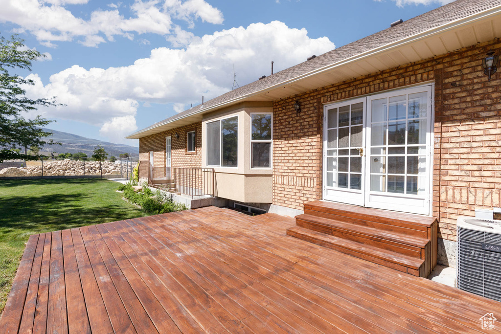 Wooden terrace with entry steps, a lawn, and a mountain view
