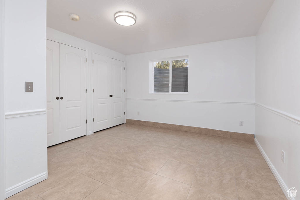 Unfurnished bedroom featuring multiple closets and light tile patterned flooring