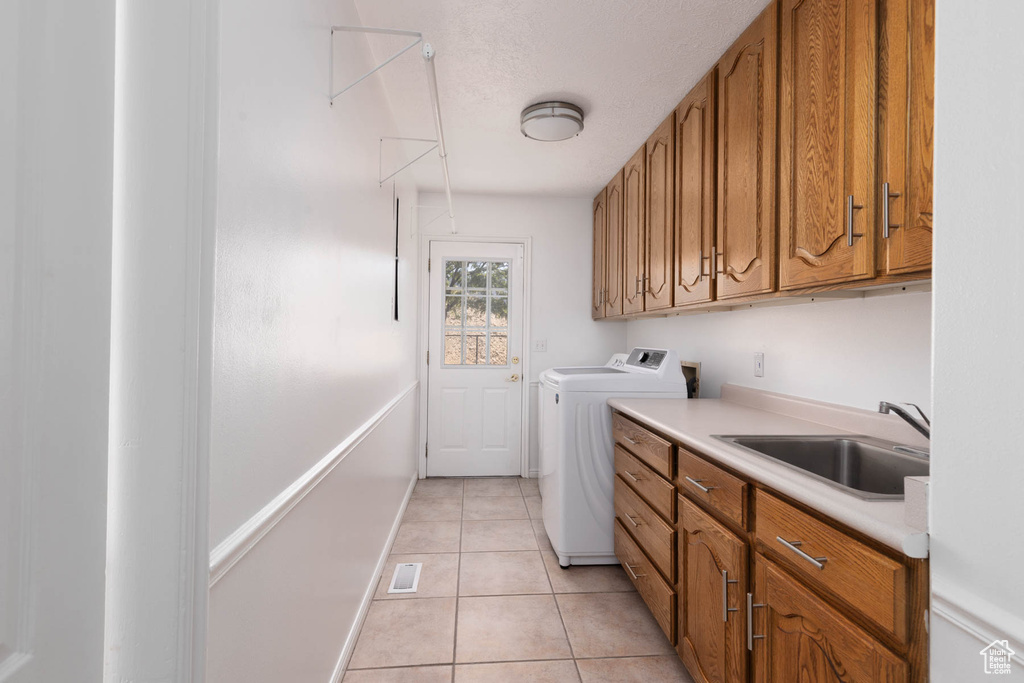 Laundry room featuring light tile patterned floors, independent washer and dryer, and cabinet space