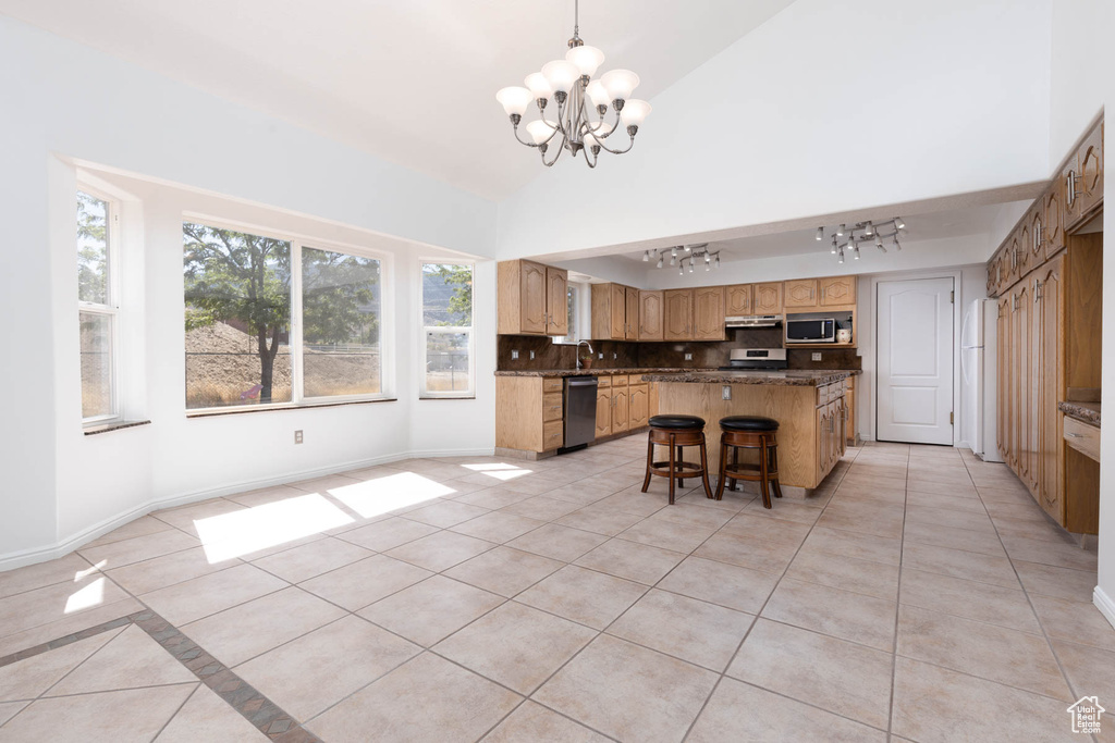 Kitchen with rail lighting, a chandelier, light tile patterned floors, backsplash, and a center island