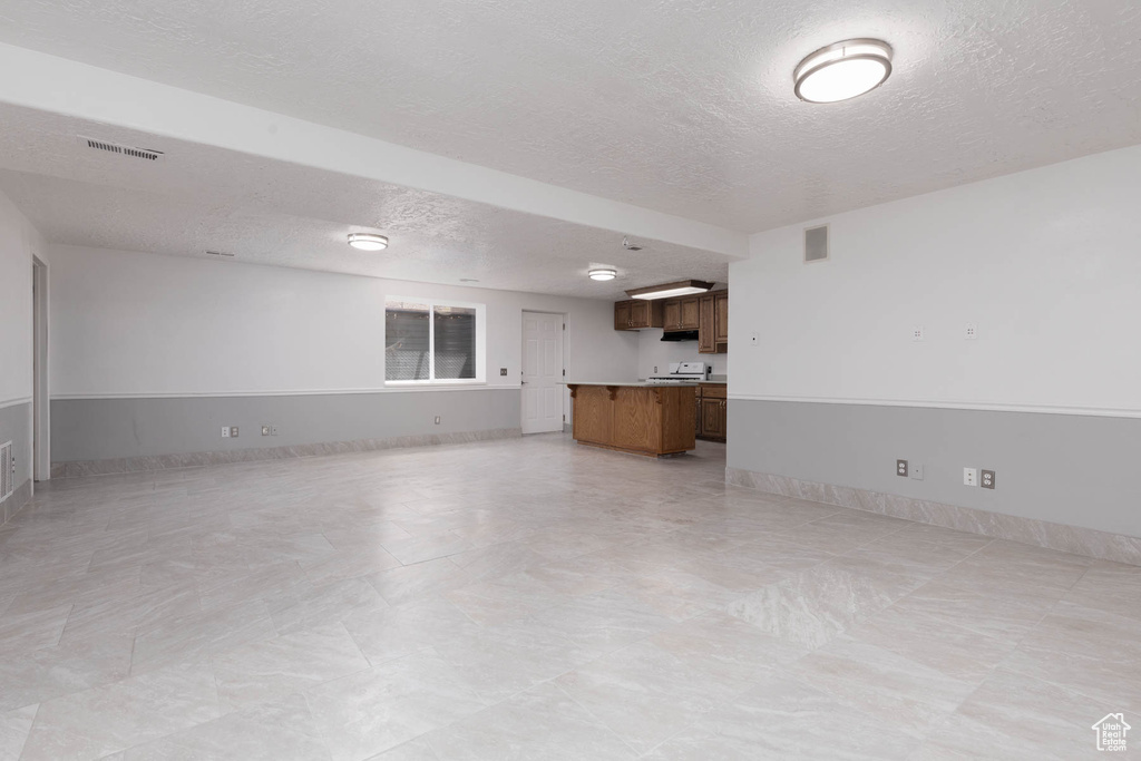 Unfurnished living room with a textured ceiling and baseboards