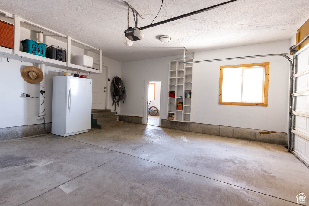 Garage with freestanding refrigerator and a garage door opener
