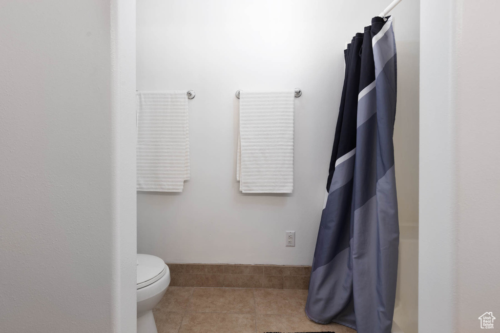 Bathroom with a shower with shower curtain and tile patterned flooring
