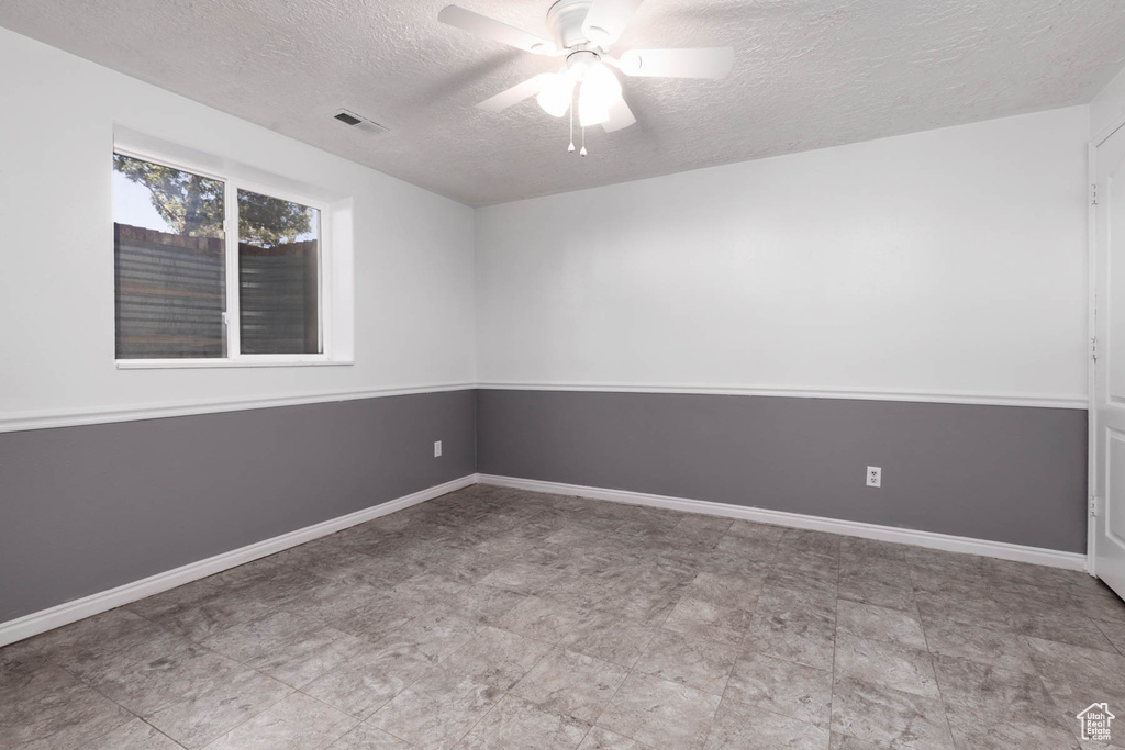 Empty room with a textured ceiling and ceiling fan