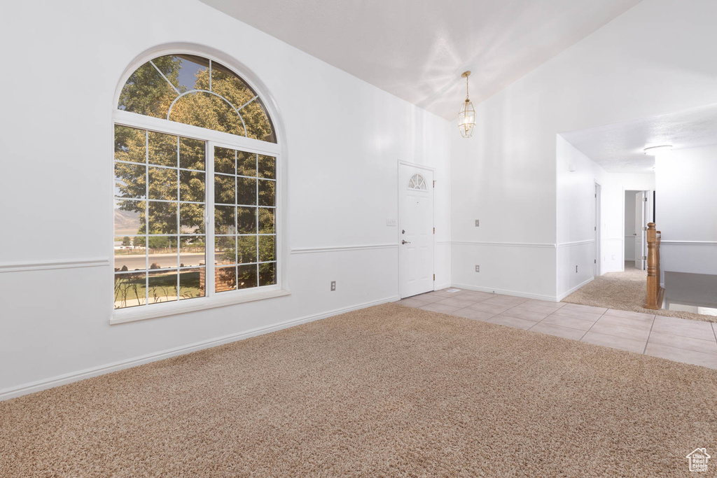 Spare room featuring light colored carpet, high vaulted ceiling, and light tile patterned flooring