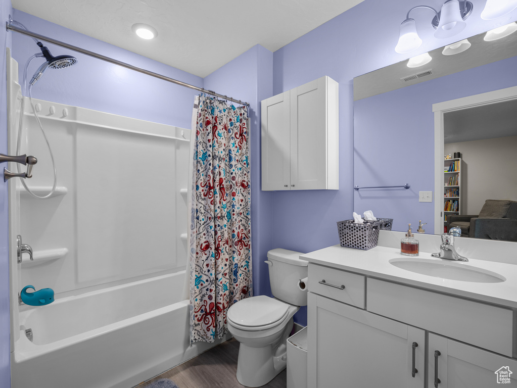 Bathroom with vanity, shower / bath combo with shower curtain, and wood finished floors