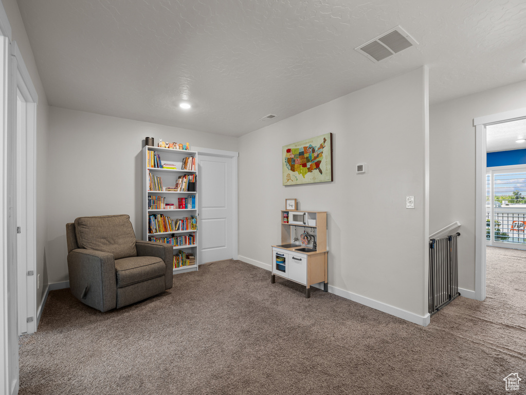 Living area with carpet flooring and an upstairs landing